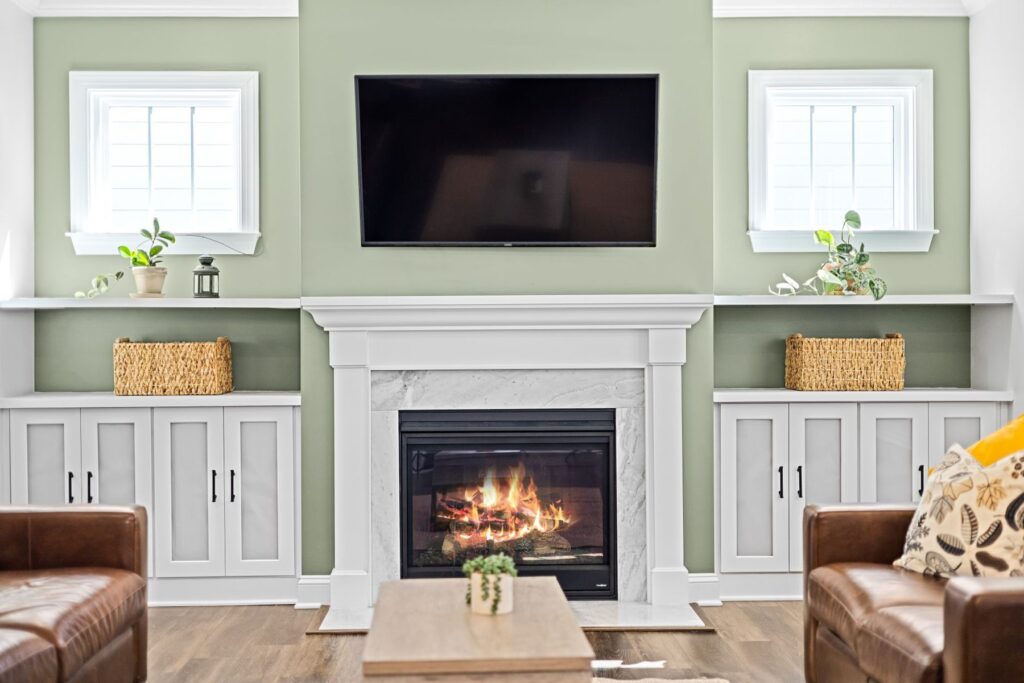 Living room with sage green walls and white built-in cabinets